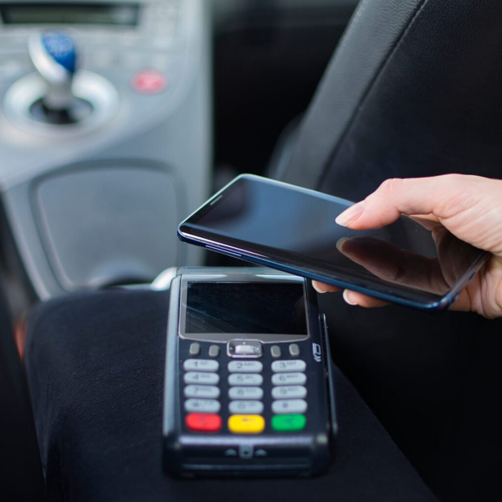 young,woman,paying,with,her,mobile,phone,for,a,cab